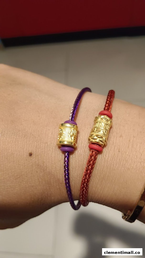 Two colorful braided bracelets with intricate gold beads on a person's wrist.