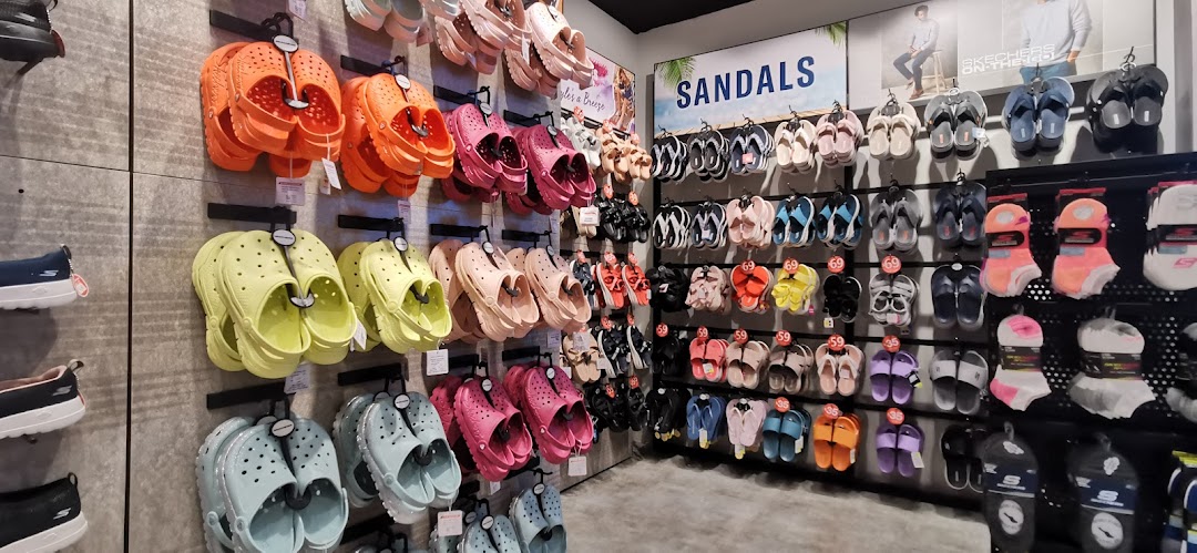 A vibrant display of Skechers sandals, clogs, and socks in various colors inside the store.