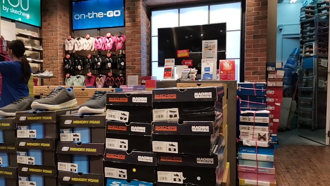 An interior view of a Skechers store showcasing various footwear, shoe boxes, and displays.