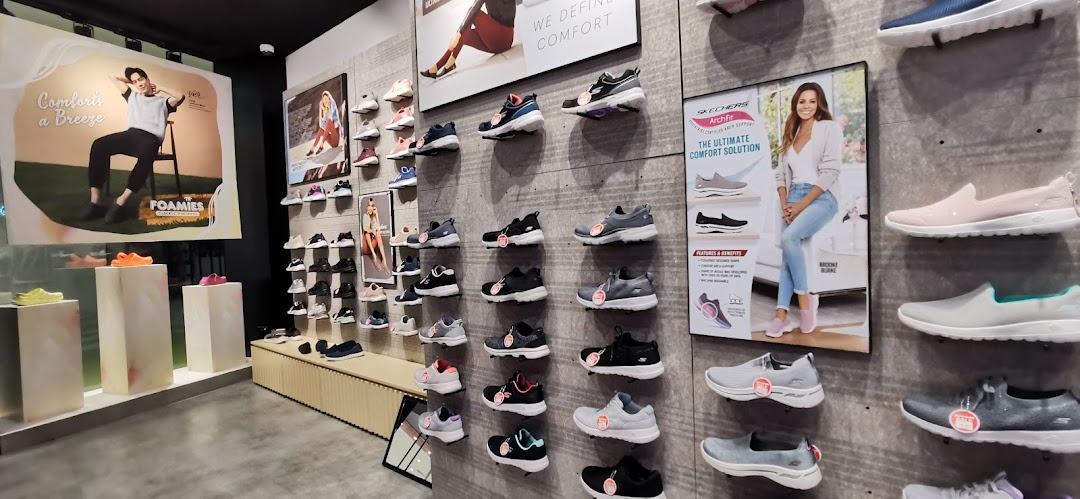 An interior view of a Skechers store showcasing various athletic and casual footwear on display walls and pedestals.