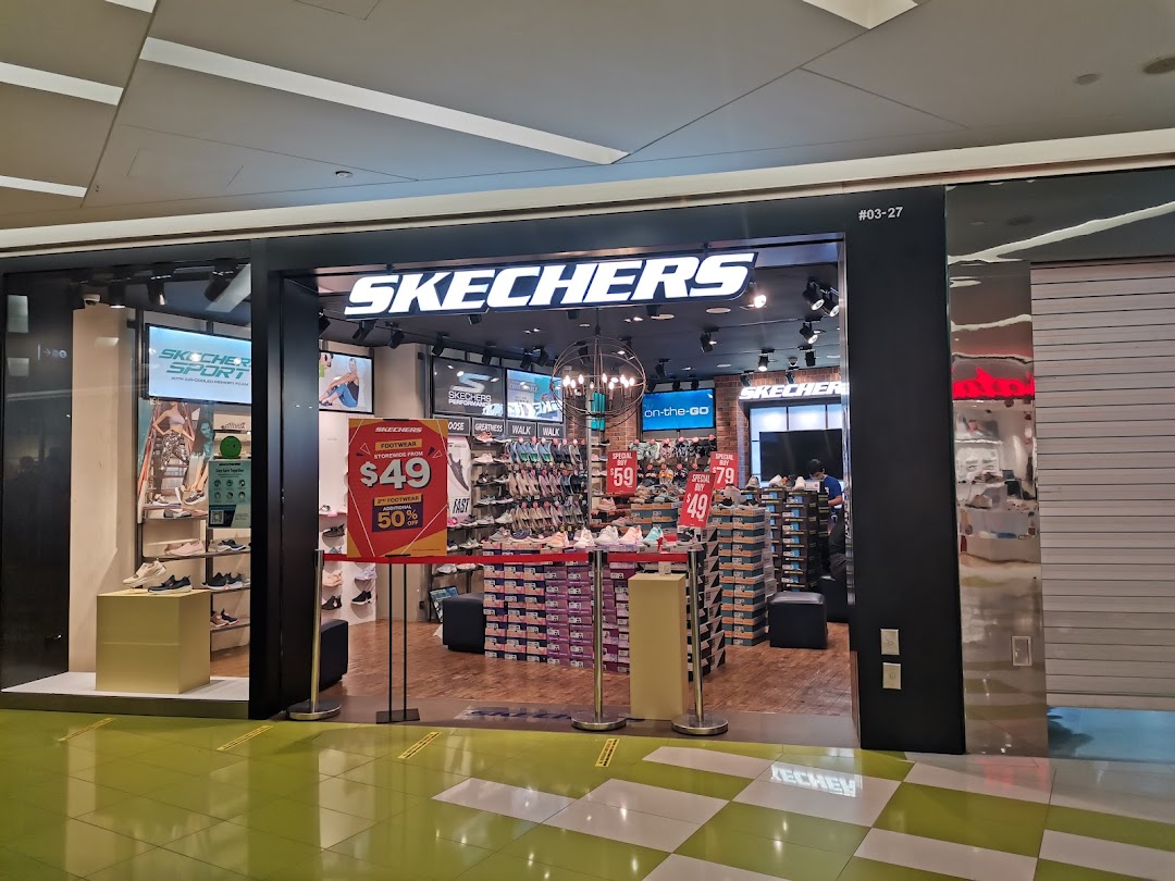 The image shows the brightly lit entrance of a Skechers shoe store with promotional signage and visible footwear displays.