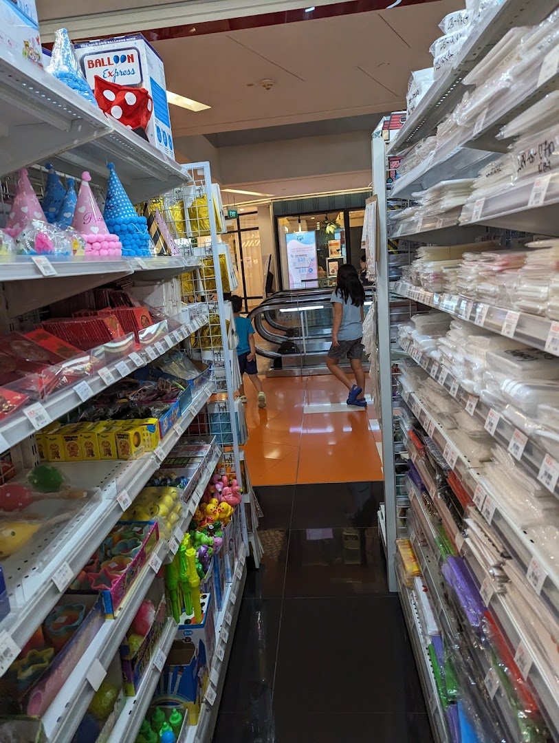 An aisle in SKP Clementi Mall, displaying shelves packed with party supplies, toys, and general merchandise.