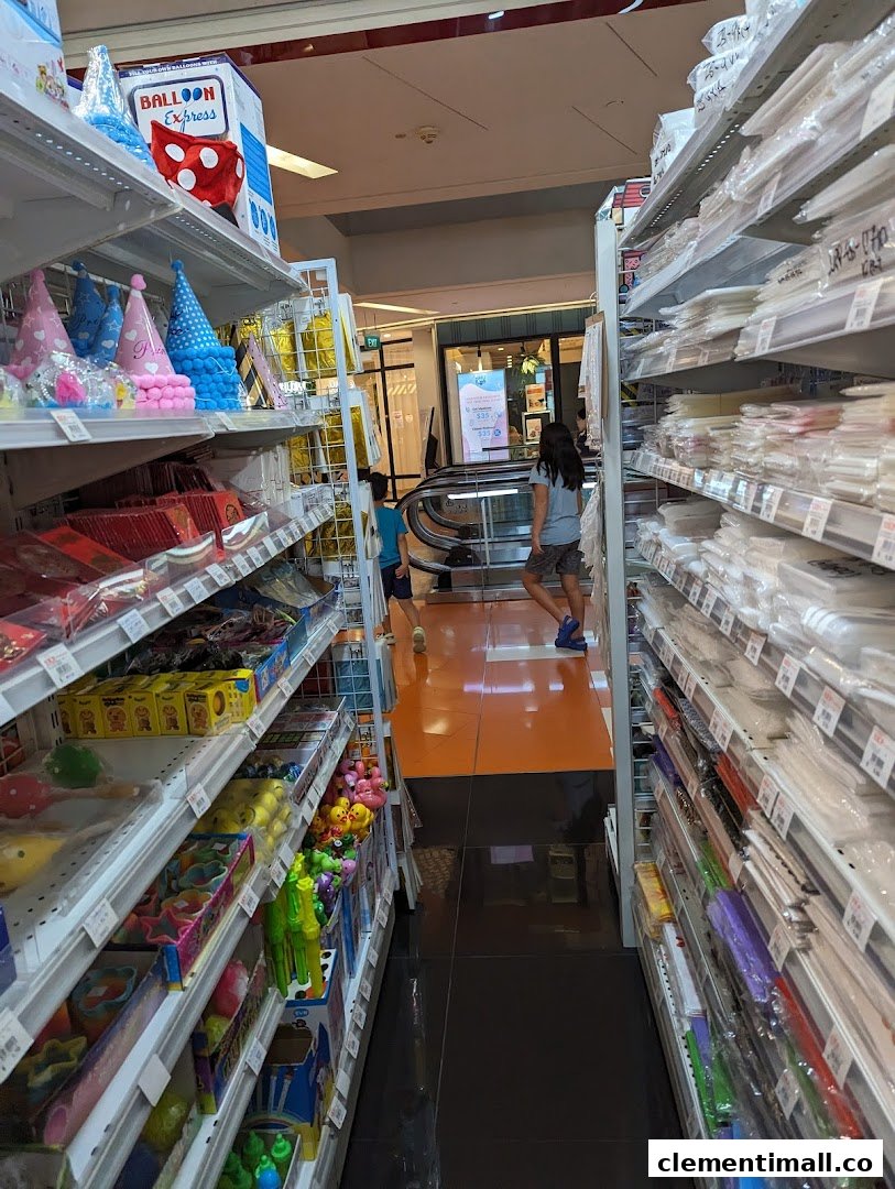 An aisle in SKP Clementi Mall, displaying shelves packed with party supplies, toys, and general merchandise.