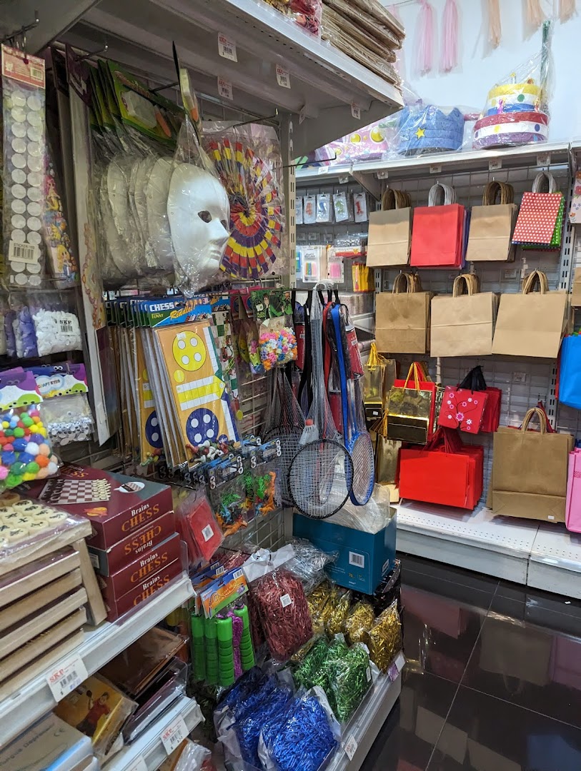 Shelves filled with party supplies, craft items, games, and gift bags in a retail store.
