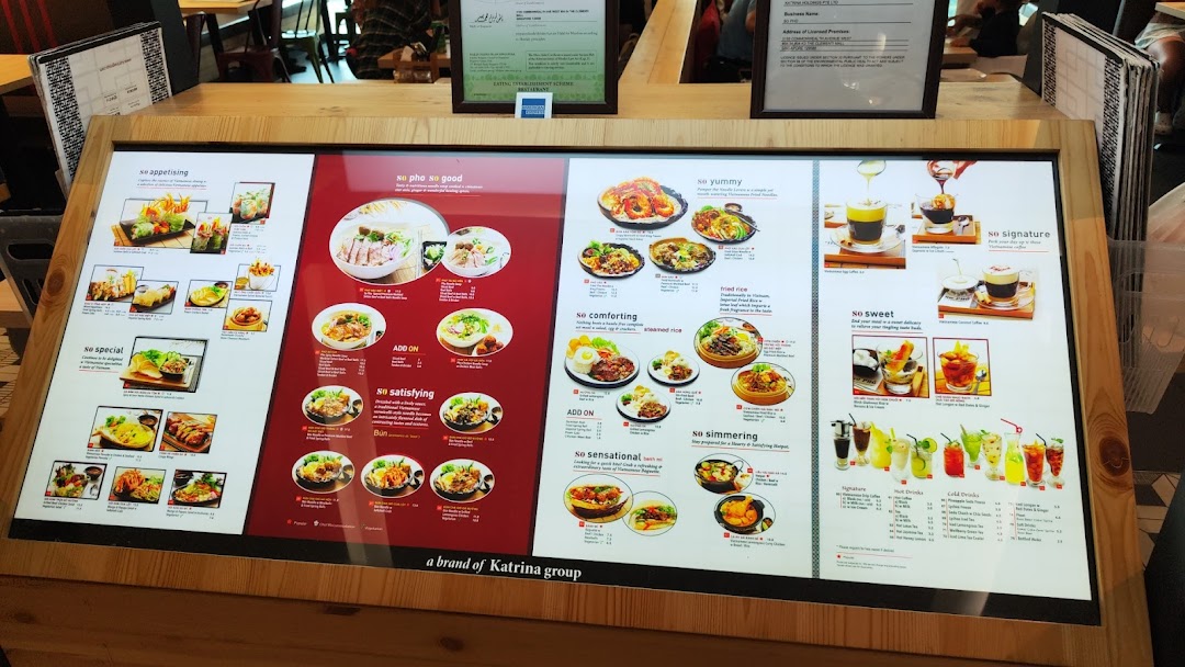 A large, illuminated digital menu board showcasing a variety of Vietnamese dishes and beverages at So Pho.