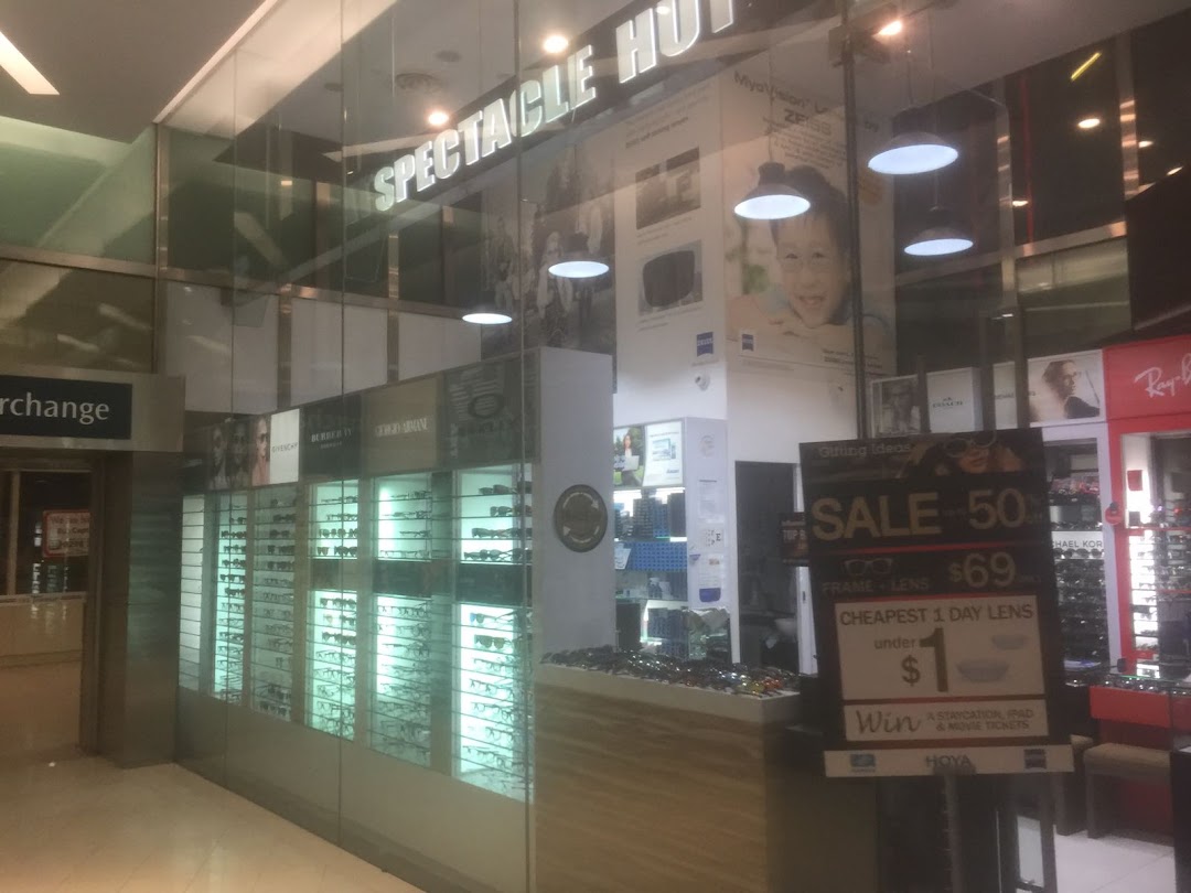 The shopfront of Spectacle Hut, an optical store, showcasing eyewear displays and a promotional sale sign.