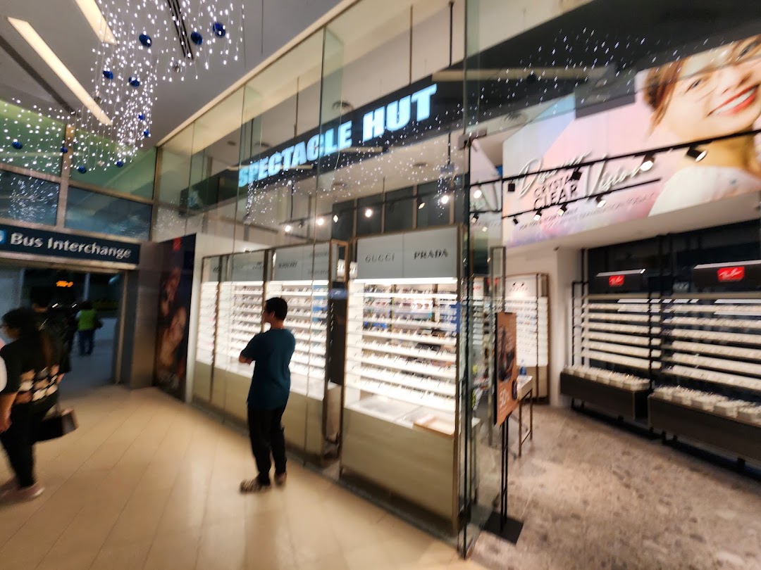 The shop front of Spectacle Hut, an optical store, featuring eyewear displays and a customer.