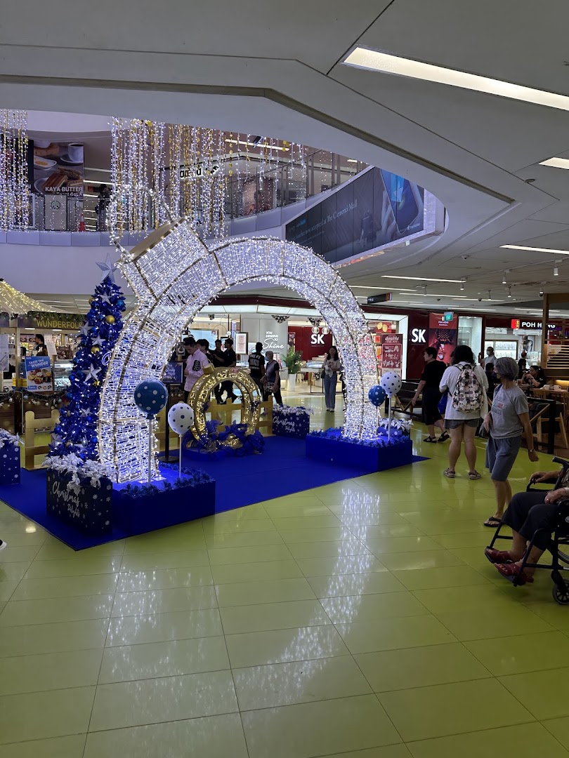 A mall interior featuring elaborate blue and white Christmas decorations and shoppers.