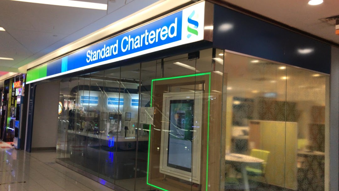 The brightly lit Standard Chartered Bank branch entrance with glass walls and digital displays.