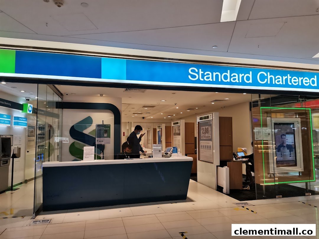 The modern glass facade of a Standard Chartered Bank branch with a customer service counter.