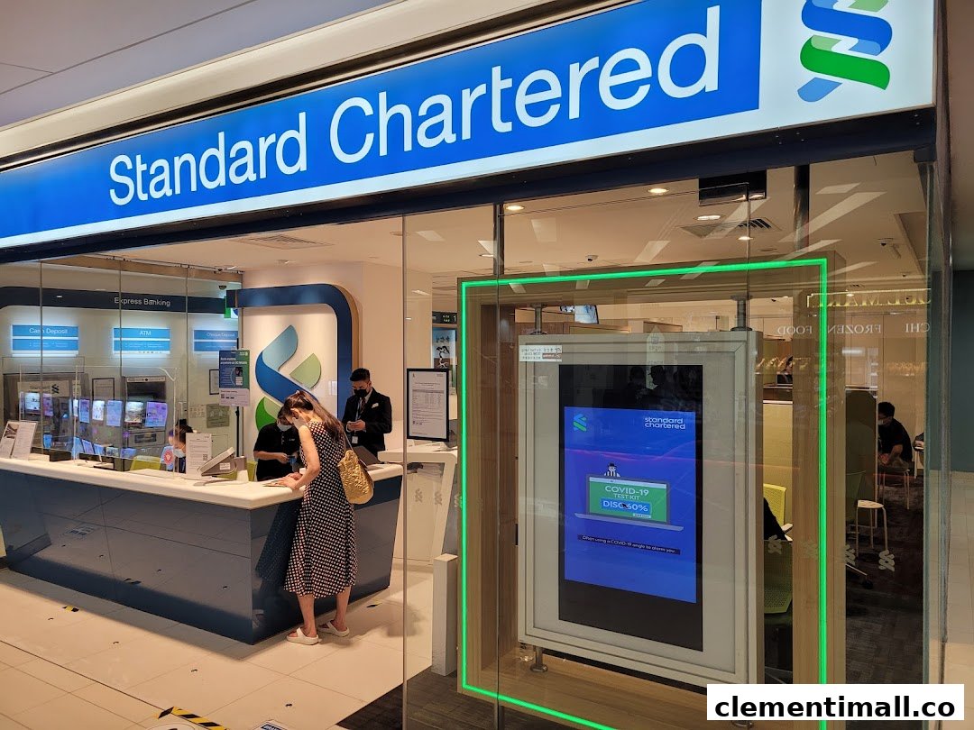 The front entrance of a Standard Chartered Bank branch with customers and staff inside.
