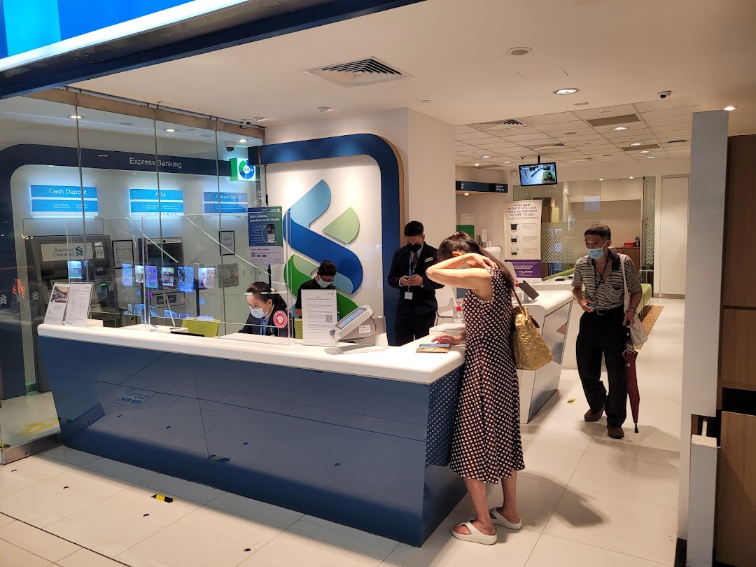 Interior view of Standard Chartered Bank with staff assisting customers and express banking machines.