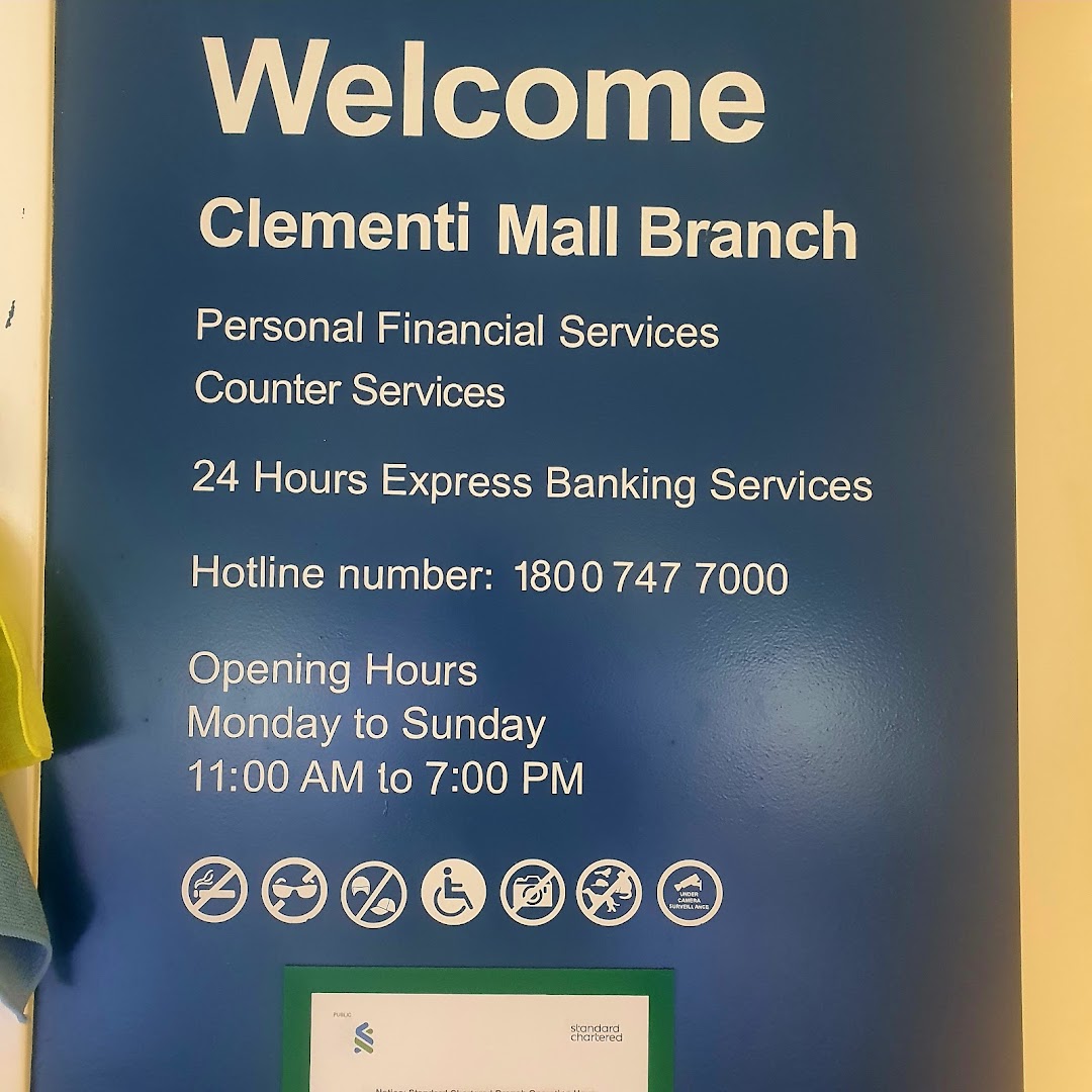 A blue informational sign for Standard Chartered Bank Clementi Mall branch detailing services, hotline, and operating hours.