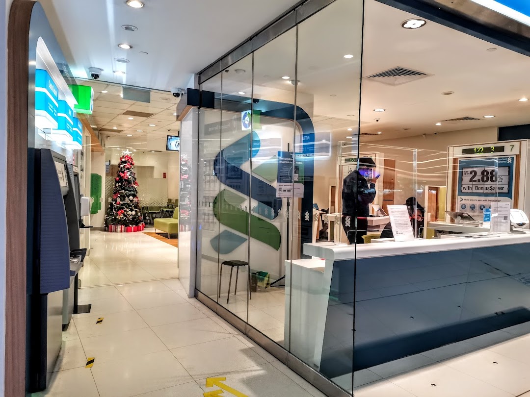 Interior view of Standard Chartered Bank, featuring ATMs, a service counter, and festive decor.