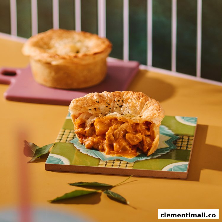 Close-up of a delicious savory pie, cut open to show its rich, flavorful filling, with another pie in the background.