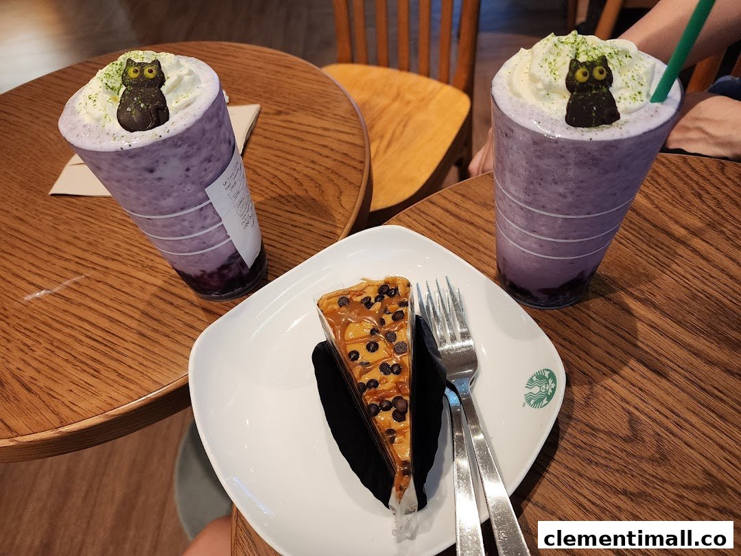 Two purple beverages with whipped cream and owl decorations, alongside a slice of cake on a wooden table.