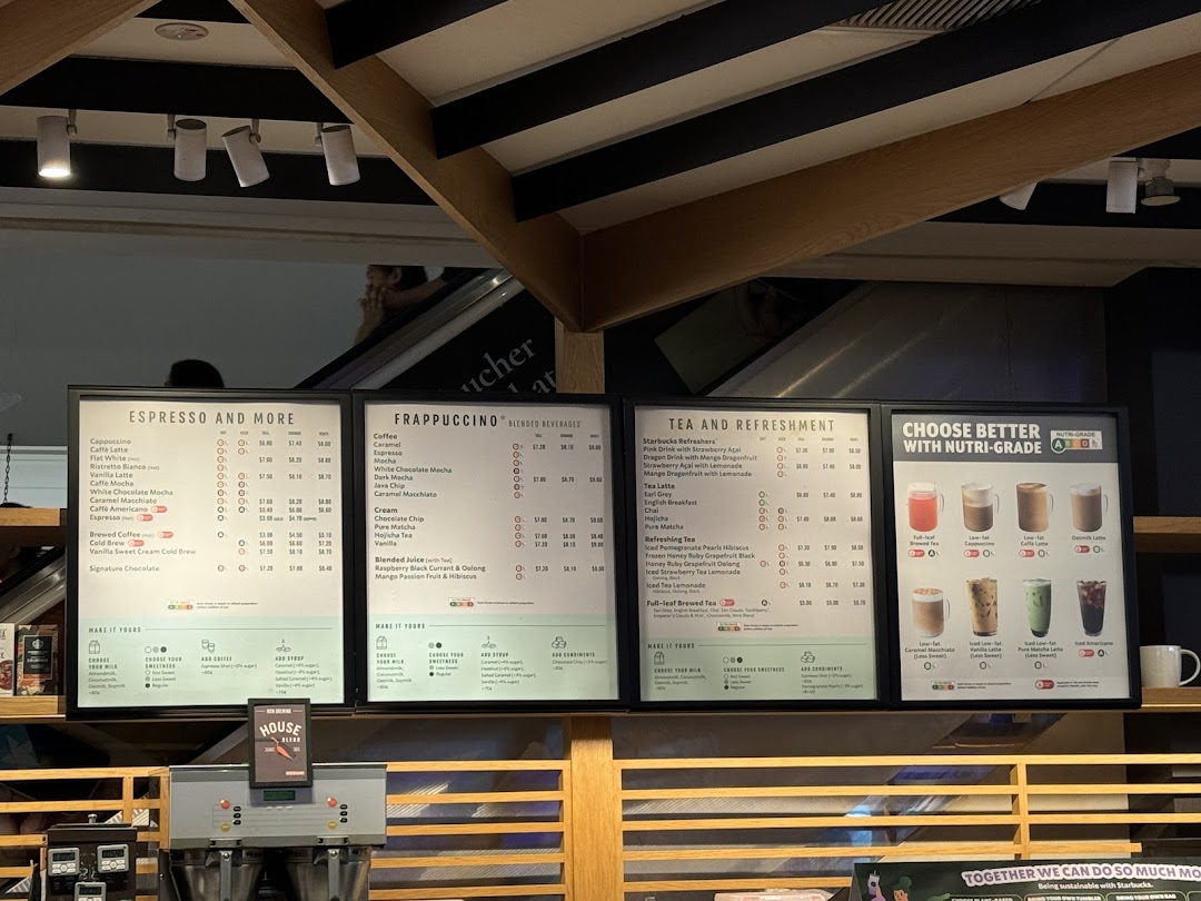 Multiple menu boards displaying coffee, frappuccino, tea, and refreshment options with prices at Starbucks.