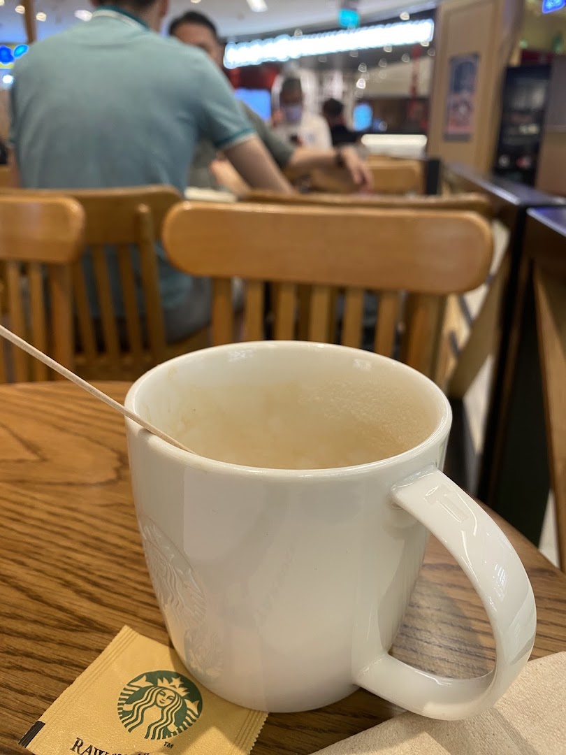An empty Starbucks mug and raw sugar packet on a wooden table inside the cafe.