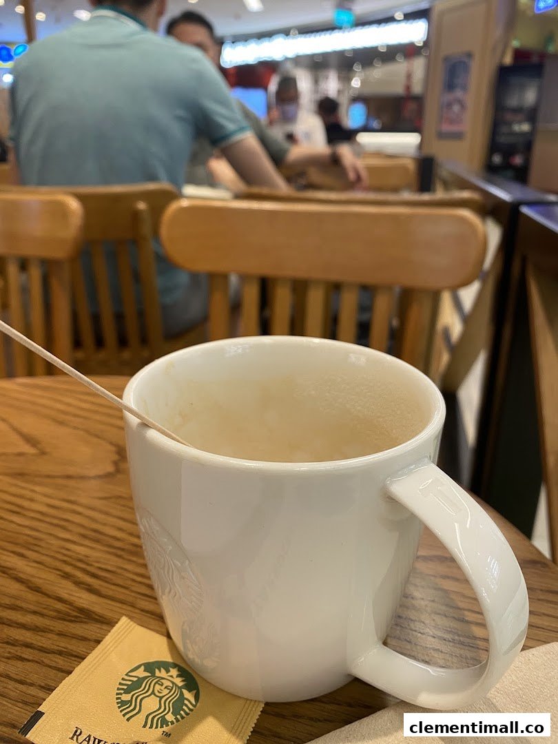 An empty Starbucks mug and raw sugar packet on a wooden table inside the cafe.