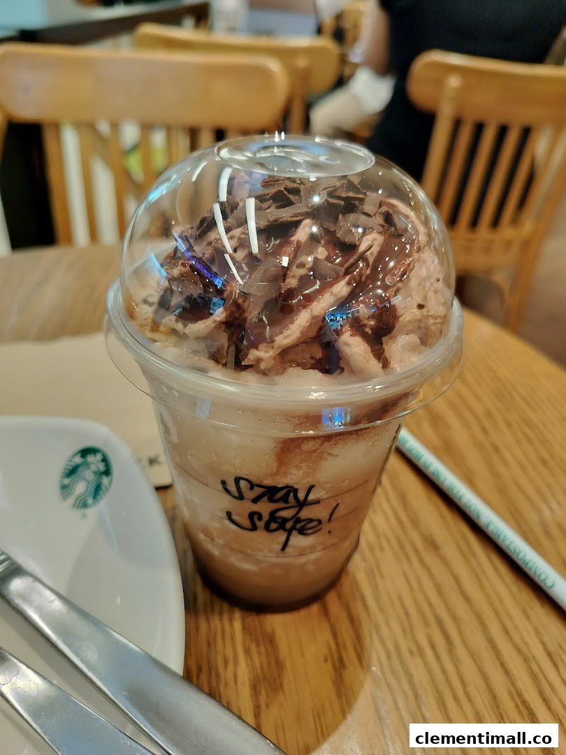 A close-up of a Starbucks Frappuccino with whipped cream and chocolate shavings on a wooden table.