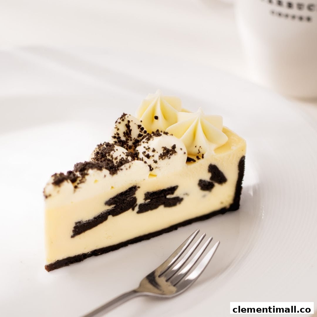 A delicious slice of cookies and cream cheesecake with a fork on a white plate.