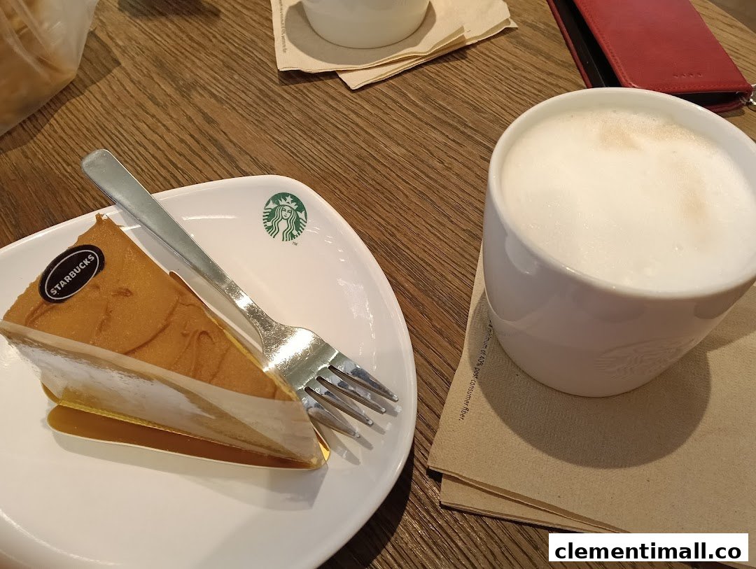 A delicious slice of cake and a frothy hot drink on a wooden table at Starbucks.