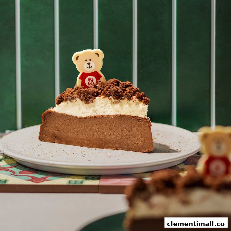 A delicious slice of chocolate and cream cake topped with cookie crumble and a bear-shaped chocolate.