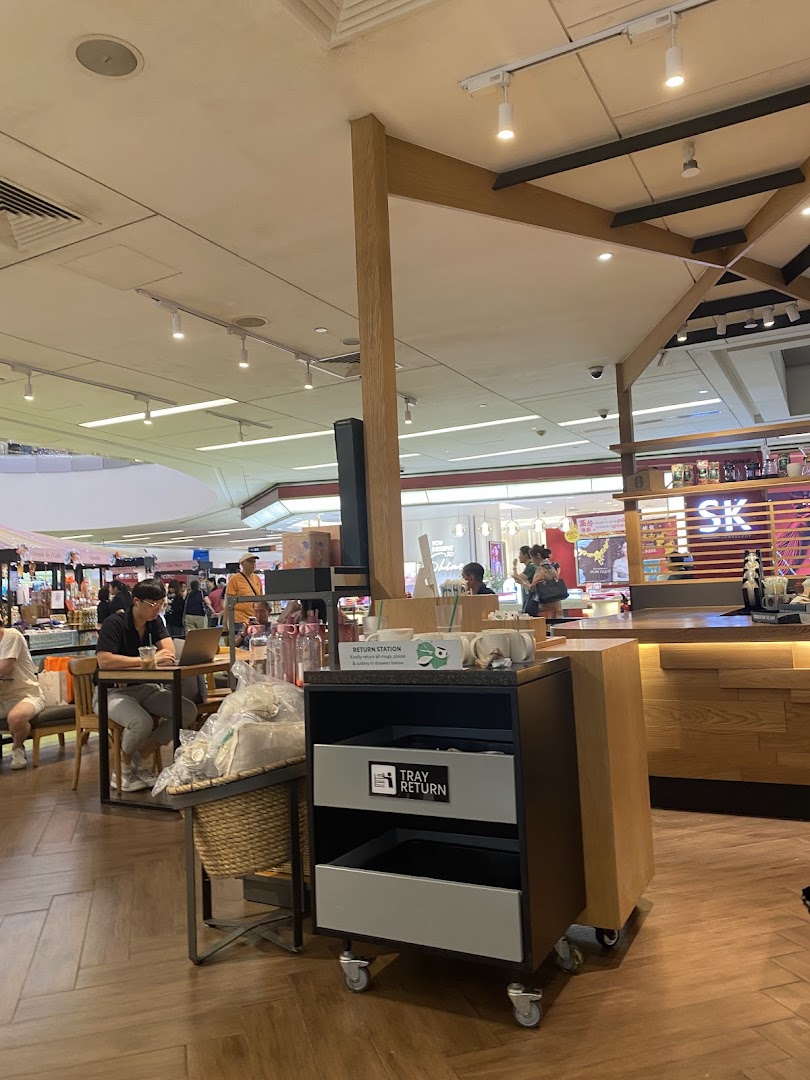 An interior view of Starbucks Clementi Mall, showing customers, a counter, and a return station.