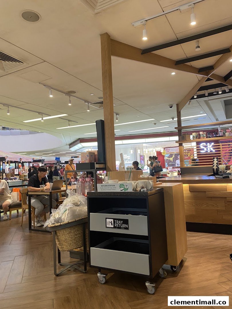 An interior view of Starbucks Clementi Mall, showing customers, a counter, and a return station.
