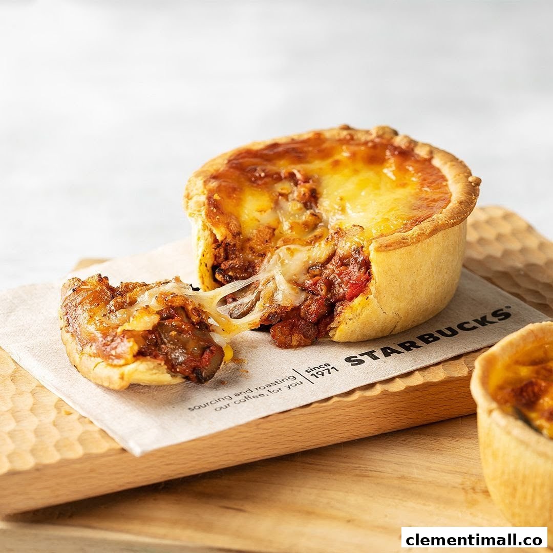 A delicious savory pie with melted cheese and rich filling, served on a wooden board with a Starbucks napkin.