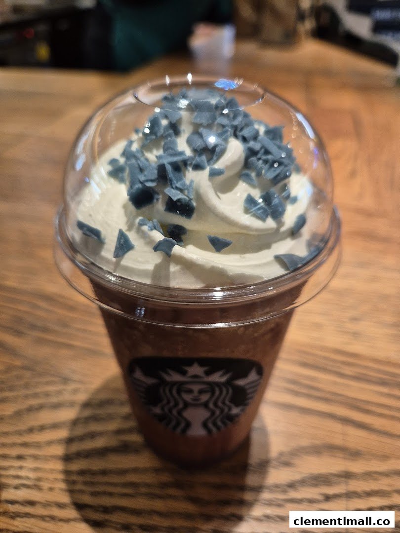 A Starbucks Frappuccino with whipped cream and unique blue toppings on a wooden table.
