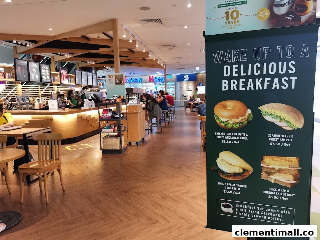 Interior view of Starbucks Clementi Mall, featuring the counter, seating, and a prominent breakfast menu banner.