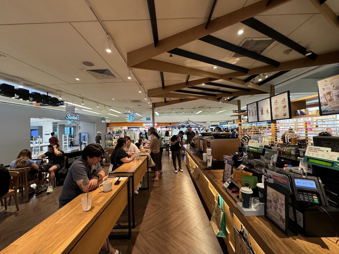 A bustling interior view of Starbucks Clementi Mall, showing customers enjoying drinks and the service counter.