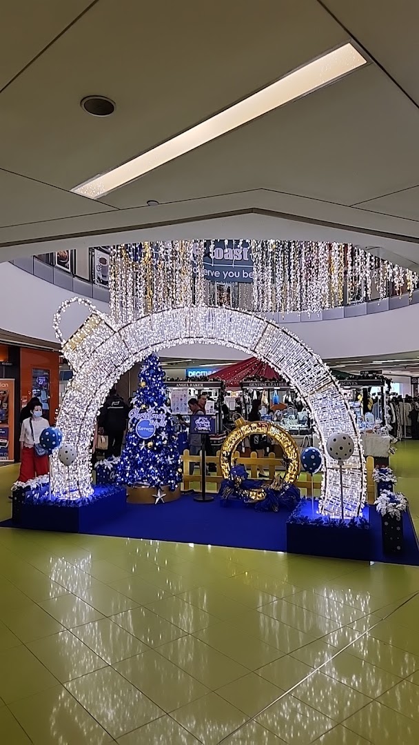 A festive mall interior featuring a large, illuminated Christmas ornament archway and a blue Christmas tree display.
