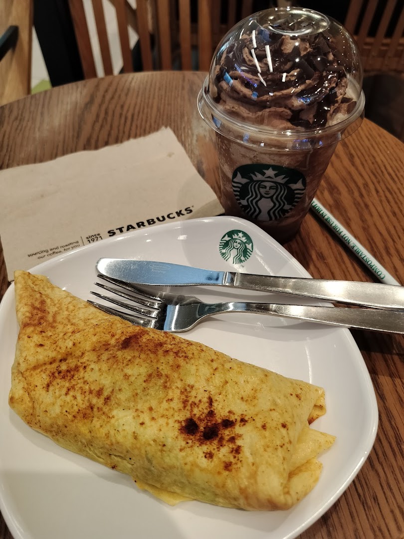 A delicious Starbucks Frappuccino and a savory food item served on a wooden table.