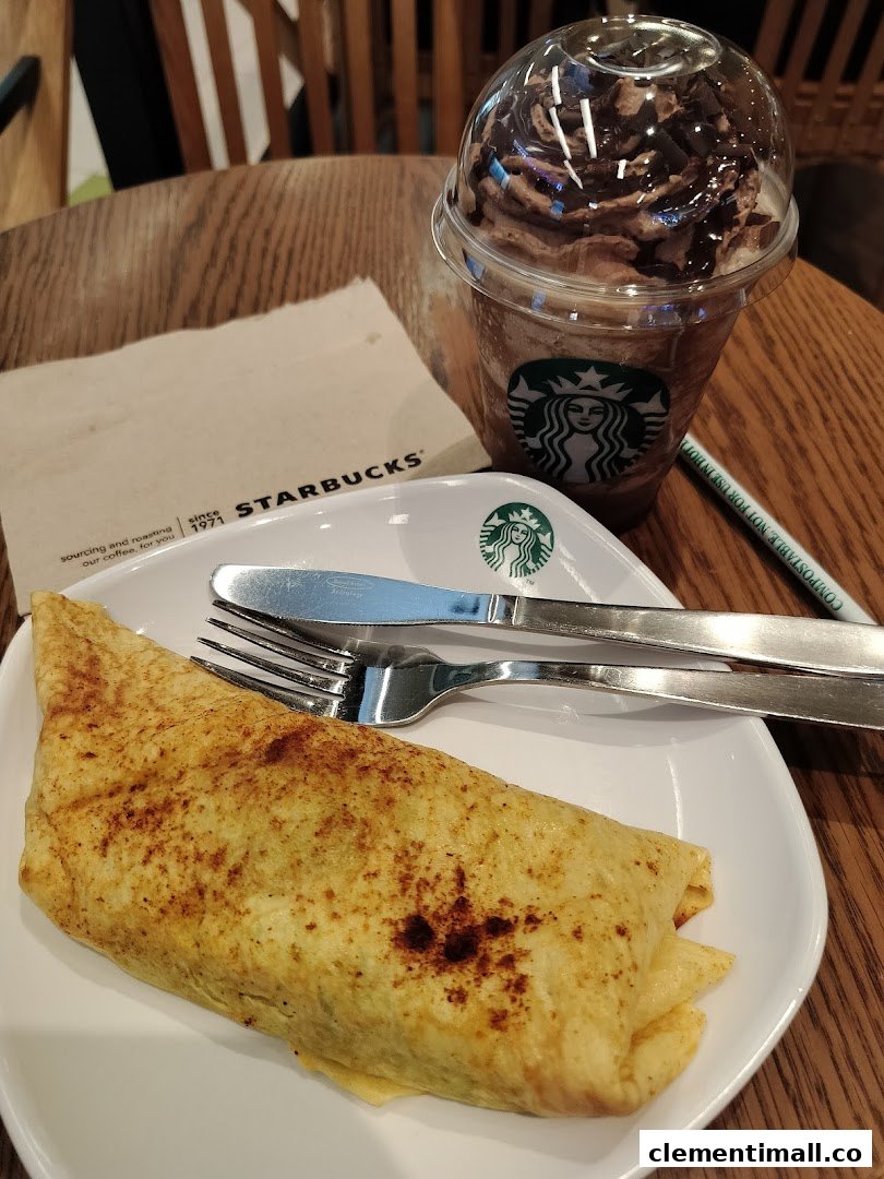 A delicious Starbucks Frappuccino and a savory food item served on a wooden table.