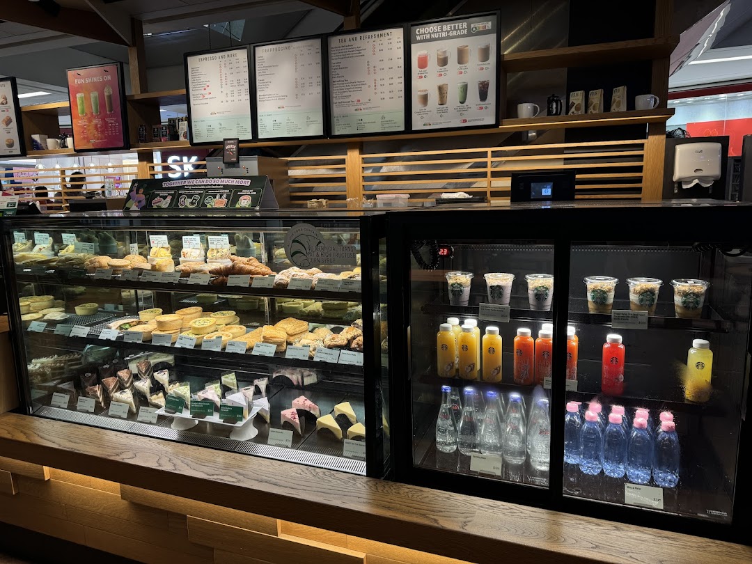 An interior view of Starbucks showcasing a vibrant display of pastries, cakes, and beverages in display cases.