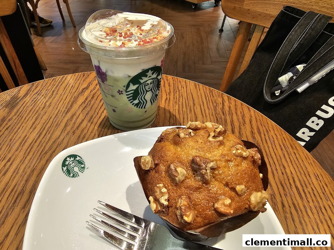 A refreshing iced drink and a delicious walnut muffin on a wooden table at Starbucks.