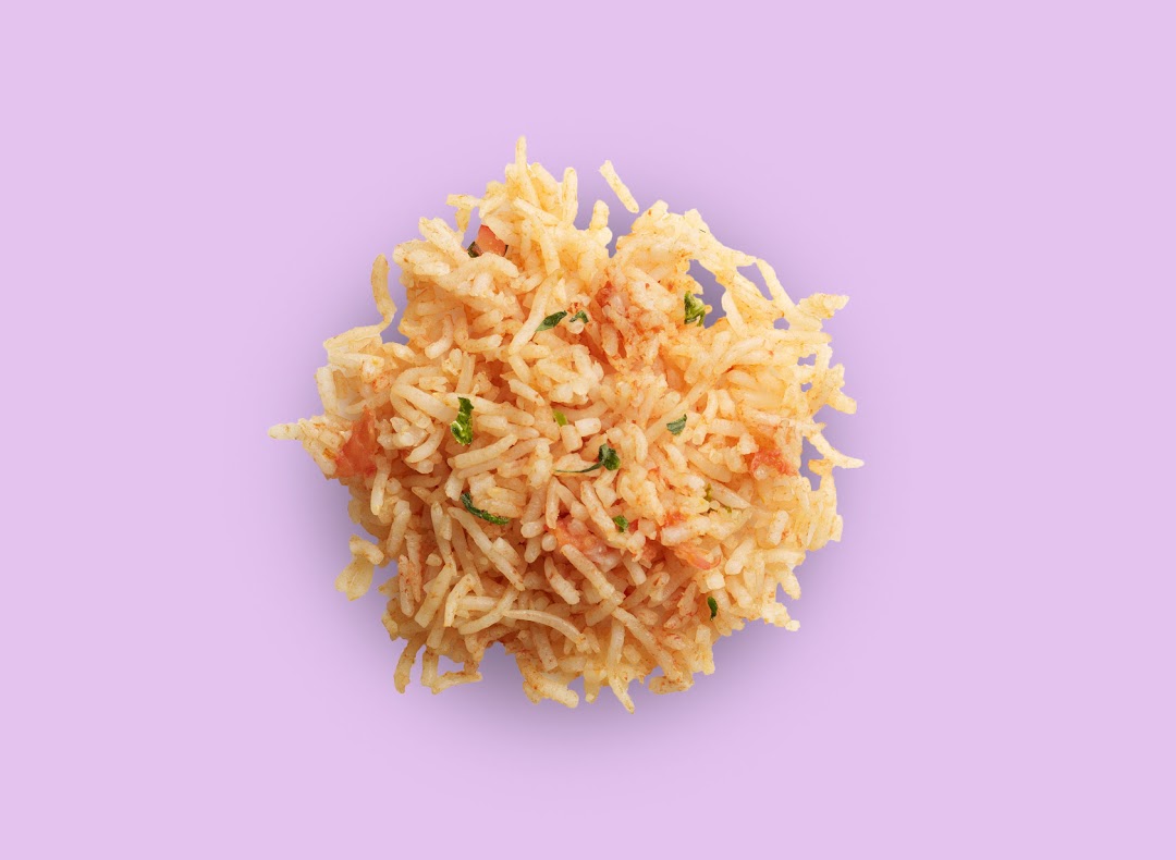 A vibrant close-up of seasoned rice with herbs and tomatoes on a light purple background.