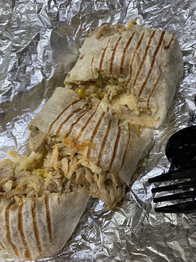 A delicious, grilled wrap filled with rice, corn, and shredded meat, served on foil.
