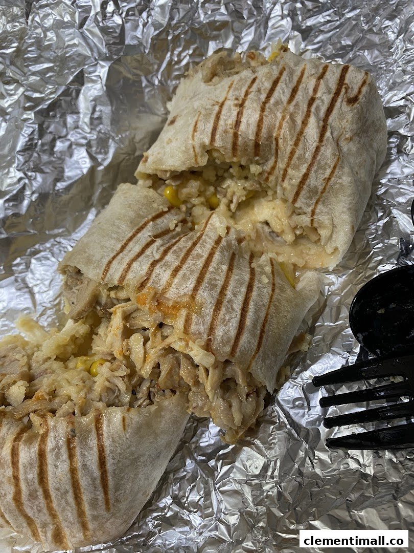 A delicious, grilled wrap filled with rice, corn, and shredded meat, served on foil.