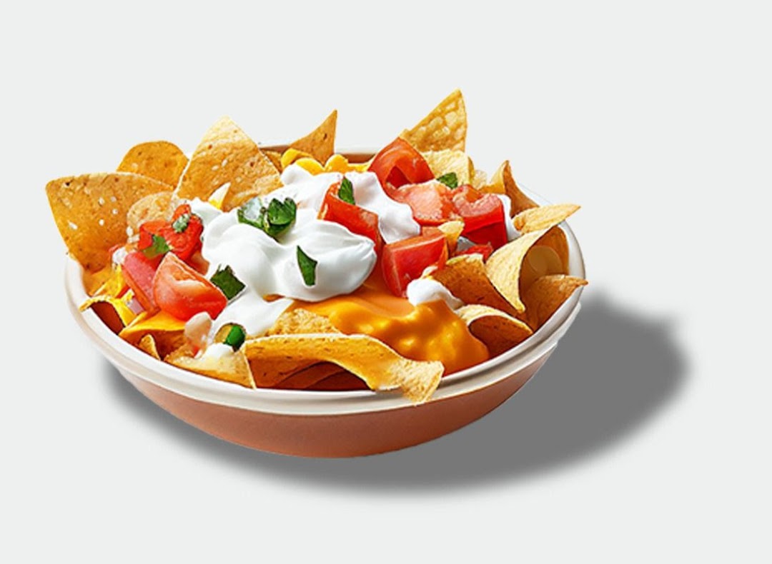 A vibrant bowl of loaded nachos with cheese, sour cream, diced tomatoes, and corn.