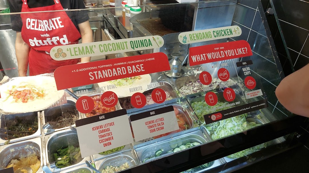 A vibrant counter at Stuffd showcasing fresh ingredients and customizable healthy meal options like kebabs and burritos.