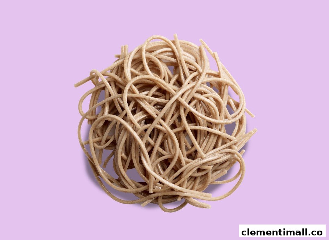 A close-up shot of a tangled pile of cooked noodles on a light purple background.