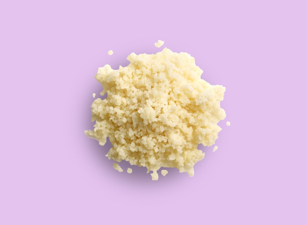 A close-up, top-down view of fluffy couscous or grains on a vibrant purple background.