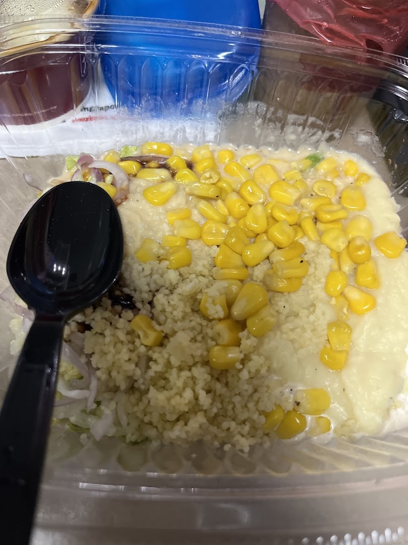 A close-up of a Stuffd salad bowl featuring couscous, corn, and fresh vegetables.