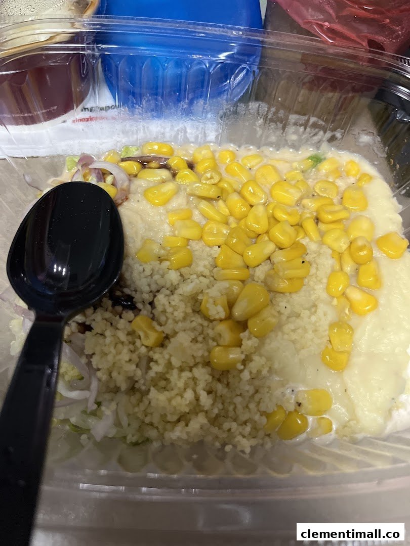 A close-up of a Stuffd salad bowl featuring couscous, corn, and fresh vegetables.