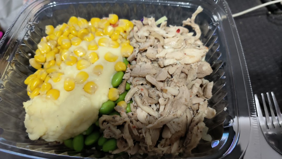 A healthy and customizable meal in a clear container featuring mashed potatoes, corn, edamame, and shredded chicken.