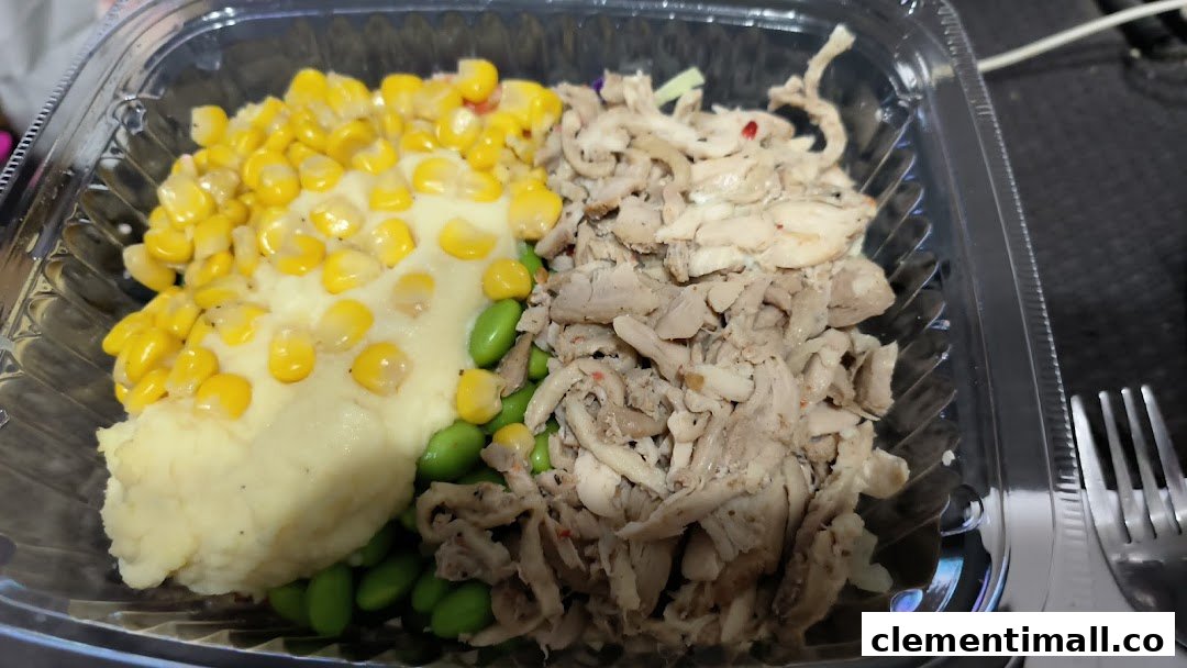 A healthy and customizable meal in a clear container featuring mashed potatoes, corn, edamame, and shredded chicken.
