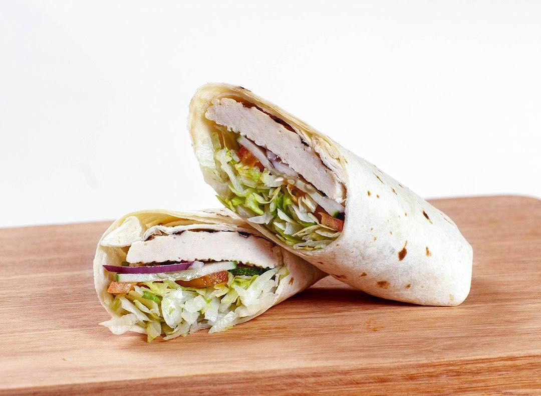 A delicious chicken and vegetable wrap, cut in half, displayed on a wooden surface.